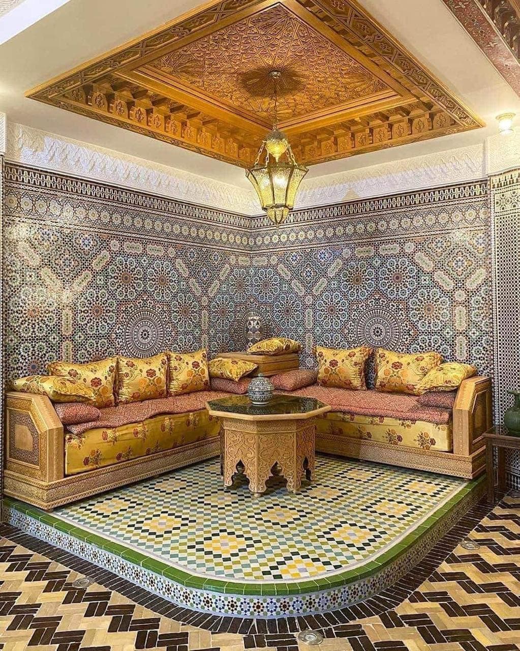 Salon traditionnel marocain en bois de cèdre avec plafond sculpté, banquettes et table octogonale