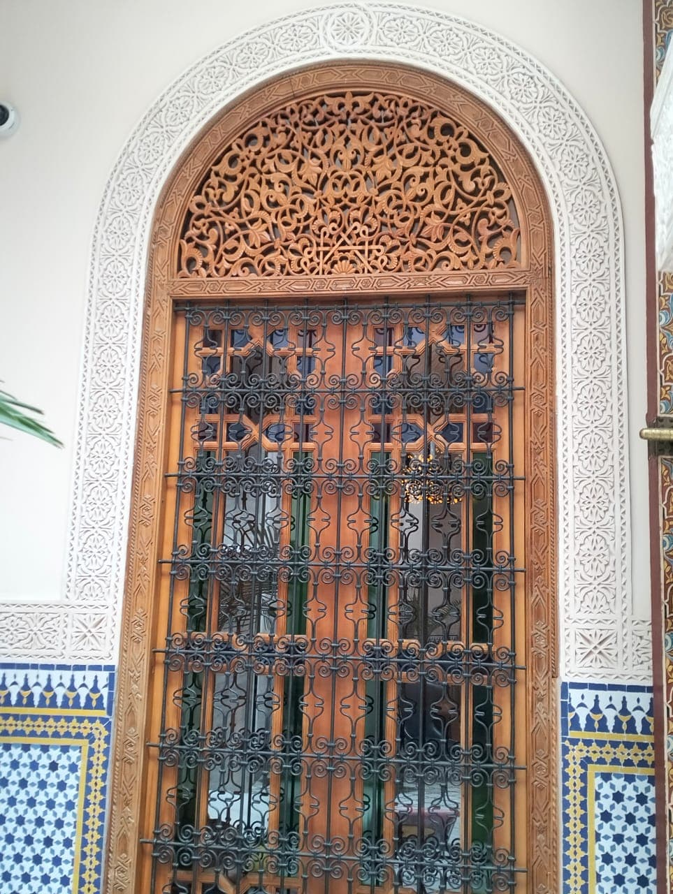 Fenêtre de portail arquée en bois de cèdre fabriquée à la main avec tympan arabesque ajouré, grille en fer forgé et arche en plâtre sculpté
